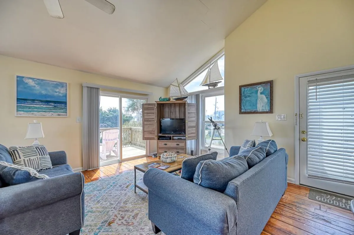 This cozy interior shot displays a comfortable living area with a sofa, television, and artwork, all bathed in natural light from sliding glass doors. While not directly showing the laundry area, it conveys the overall comfort and practical design of the home’s main living spaces, which are all on one level.