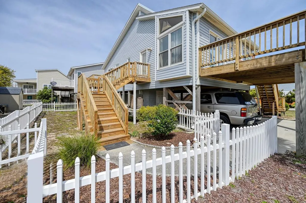 A fenced yard stretches beneath wooden stairs, surrounded by neat landscaping. The space feels inviting for families and pets, and ties in with the deck and outdoor gathering areas.