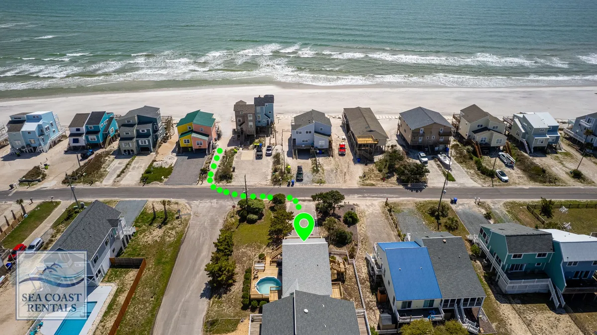 A cheerful exterior view of colorful beachfront homes, a sandy walking path, and a glimpse of the beach, capturing the relaxed and vibrant atmosphere of the surrounding neighborhood. The image hints at easy access to beach activities and local attractions.